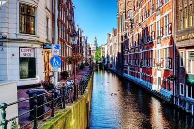 Canal amidst city buildings against sky