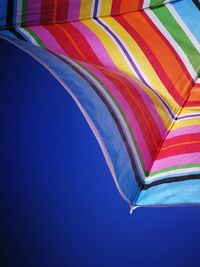 Low angle view of flags against clear blue sky