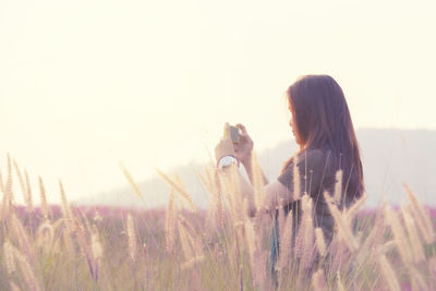 Side view of woman standing on field against sky