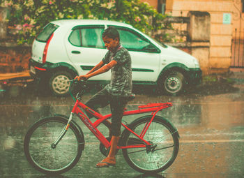 Boy riding bicycle on road during rainy season