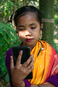 A tribal little girl is listening to music with bluetooth headphones on her android phone