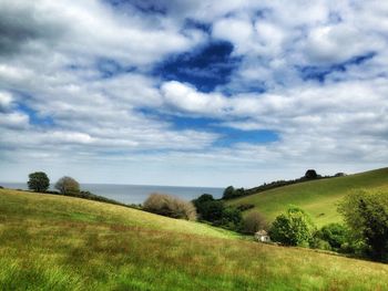 Scenic view of grassy field against cloudy sky