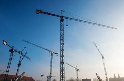 Low angle view of cranes against sky