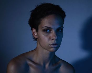 Portrait of young woman against blue background