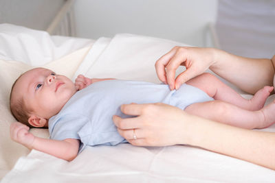 Midsection of doctor examining patient lying on bed at home