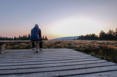 Rear view of man on walkway at sunset