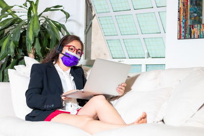 Young woman using mobile phone while sitting on bed