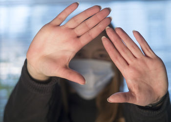 Close-up of woman wearing a medical mask and stop gesturing with both hands