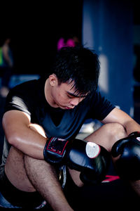 Close-up of boxer looking down while sitting in gym