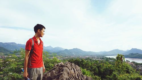 Young man looking at mountains against sky