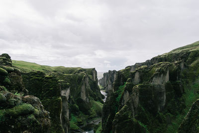 Scenic view of cliff against cloudy sky