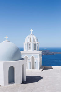 Church with sea in background against clear blue sky