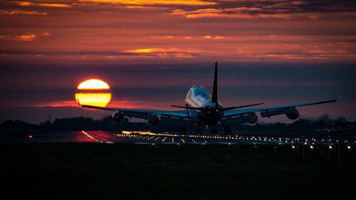 Airplane flying in sky at sunset