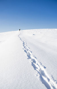 Person skiing on snow covered land against sky