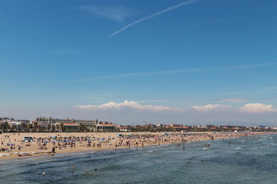 People on beach against sky in city