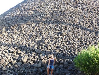 Woman sitting on heap of rocks at beach