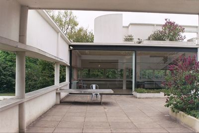 Empty chairs and table outside house in yard against sky