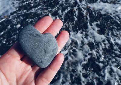 Close-up of hand holding heart shape stone