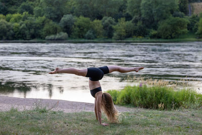 Rear view of young woman with arms outstretched standing in lake