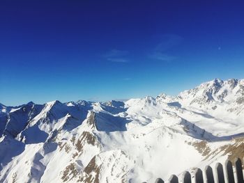 Low angle view of snowcapped mountains against blue sky