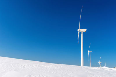 Low angle view windmill on field against sky during winter
