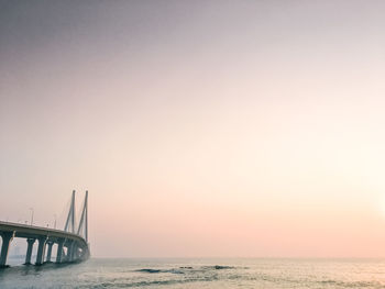 Bridge over sea against clear sky during sunset