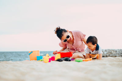 People with toy on beach against sky