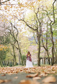 Woman standing by tree in forest