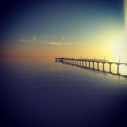 Pier over sea against sky during sunset