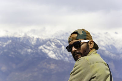 Portrait of man standing on snowcapped mountain against sky