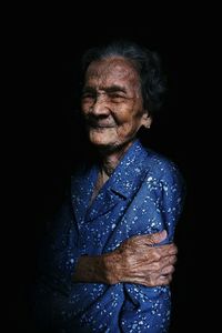 Smiling senior woman against black background