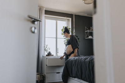 Pregnant woman organizing drawers in bedroom and getting ready for baby arrival