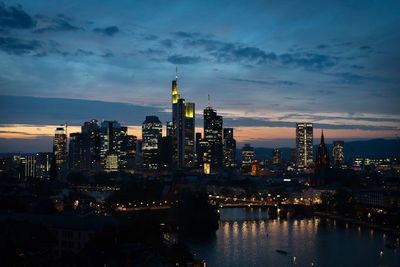 Illuminated buildings in city against sky at dusk