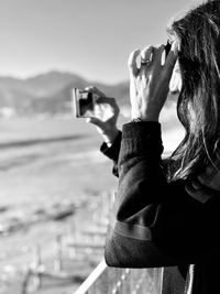 Side view of woman photographing with mobile phone