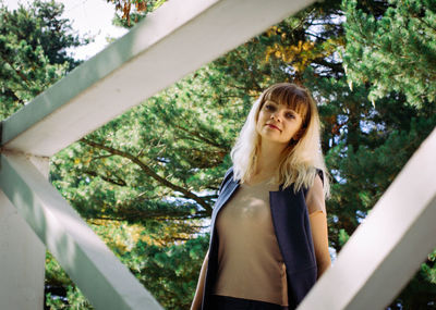 Portrait of woman standing against trees in park