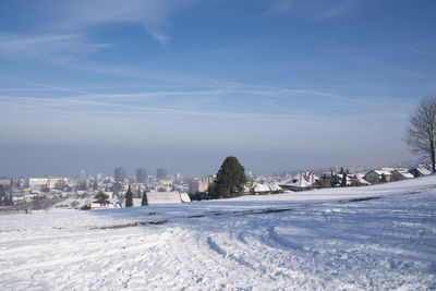 Snow covered land and buildings against sky
