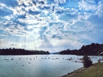 View of boats in calm sea against cloudy sky