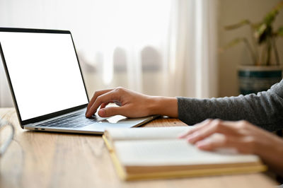 Midsection of woman using laptop on table