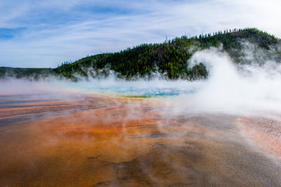 Scenic view of hot spring against mountain and sky