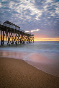 Pier over sea against sky during sunset