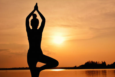 Silhouette of woman doing yoga against sky during sunset