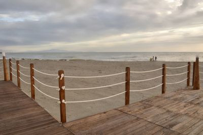 Wooden posts on beach against sky