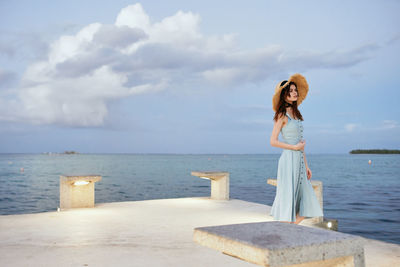 Woman standing by sea against sky