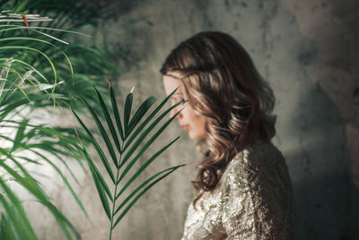 Woman with plant against wall