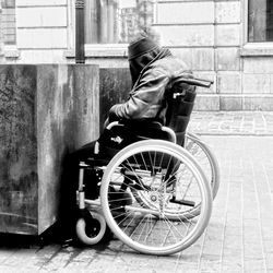 Side view of a man sitting with bicycle on street