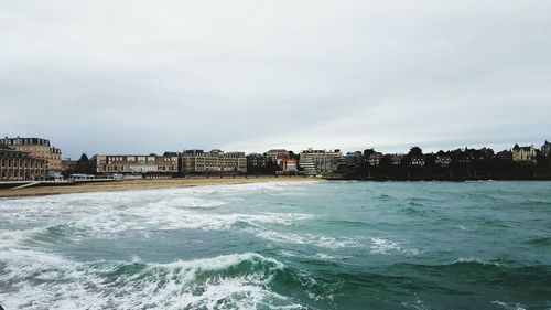 Scenic view of sea and cityscape against sky