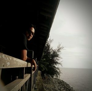 Young man looking at sea against sky