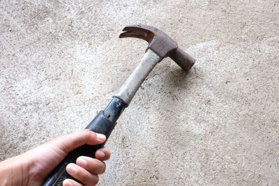 Cropped hand of man hammering wall