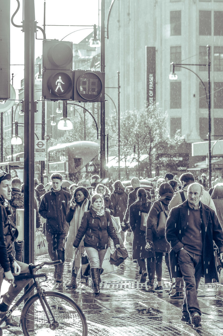 PEOPLE WALKING ON CITY STREET DURING RAINY SEASON