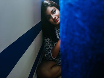 Portrait of young woman standing against gray background
